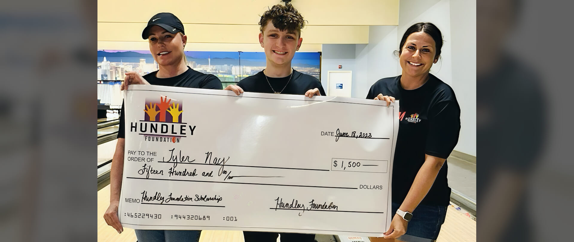 three members of "The Team" holding a giant check for $1,500